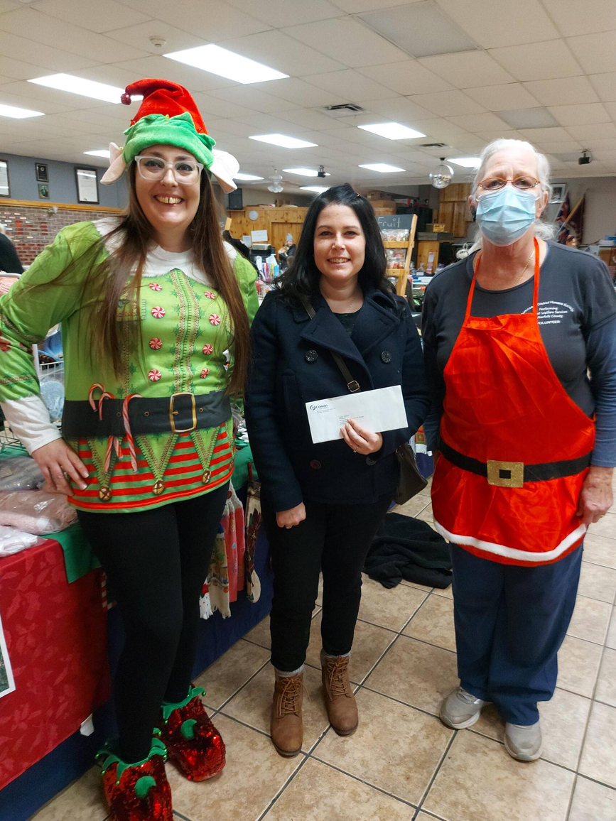 Volunteer presenting cheque to members of charity dressed in Christmas costumes